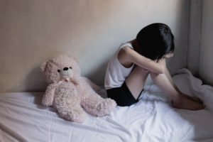 A young girl sitting on a bed. A lawyer can explain Penal Code 311 PC | Possession of Child Pornography. 