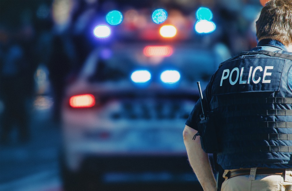 The back of a uniform Police Officer by a Police vehicle on the